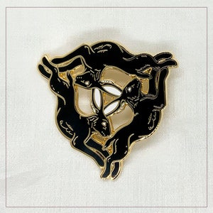 May include: Black enamel pin featuring three stylised black rabbits in a circle, with white accents on their ears and tails.