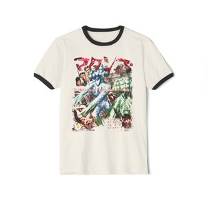 May include: A white t-shirt with a black ringer neck. The shirt features a vintage Japanese movie poster graphic with the text "マジンガーZ" and a scene of a giant robot fighting.