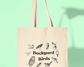 May include: A beige canvas tote bag with black handles and a black graphic of various birds with the text "Backyard Birds" in the center.