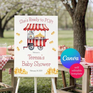 Puede incluir: Un letrero blanco sobre un caballete con el texto "She's Ready to POP!" y "Baby Shower de Teresa, 24 de febrero de 2029." Se presenta una ilustración de acuarela de un carrito de palomitas de maíz rojo y blanco. También se ven los logotipos de Canva y plantilla editable.
