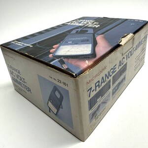 May include: A brown cardboard box with a white label that says "MICRONTA 7-RANGE AC VOLT-AMMETER" and a picture of a black and blue volt-ammeter. The box has a white label with the text "Cat. No. 22-161" and a picture of the volt-ammeter.