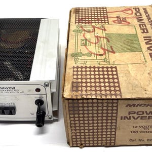 May include: A silver Micronta power inverter with a black mesh top and a cardboard box. The inverter has black and red terminals and a 300-watt rating. The box is labeled "Micronta Power Inverter" and "12 Volts DC to 120 Volts AC."