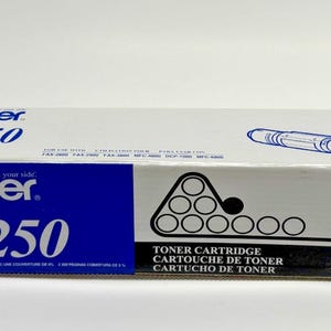May include: A white and blue Brother TN-250 toner cartridge box. The box features the Brother logo, the product name, and the words "Toner Cartridge" in English, French, and Spanish. A diagram of the toner cartridge is also visible.