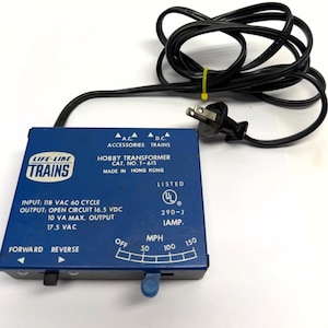 May include: A blue Life-Like Trains hobby transformer with a black power cord. The transformer has text that reads "HOBBY TRANSFORMER CAT. NO. T-615" and "INPUT: 118 VAC 60 CYCLE". It features a speed dial and forward/reverse switch.