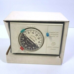 May include: A white GE Home Sentry Timer with a round clock face and a black dial. The clock face has black numbers and markings for AM and PM. The timer has three knobs: Manual Off, Automatic, and Manual On.