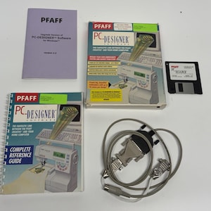May include: A Pfaff PC-Designer software package for Windows, including a spiral-bound reference guide, a purple manual, a software box with an illustration of a sewing machine, a 3.5-inch floppy disk, and a gray serial interface cable.