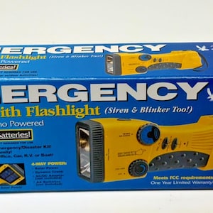 May include: A rectangular blue cardboard box for a Falcon Enterprises emergency radio with flashlight. The box features yellow text and graphics of a yellow, solar and dynamo-powered handheld device with a siren and blinker function.