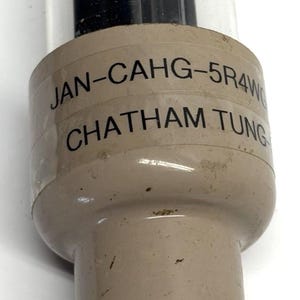 May include: Vintage vacuum tube with a clear glass enclosure and a beige base. The tube has the text "JAN-CAHG-5R4W" and "CHATHAM TUNG" printed on it. The tube has several pins at the bottom.