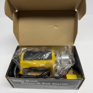 May include: A new Deluxe 12-Volt Starter by Hobby Shack, packaged in a cardboard box. The starter is yellow and silver, with black wiring. The box has the product name printed on it.