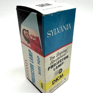 May include: Vintage Sylvania projector lamp box. The box is white, blue, and yellow with the text "SYLVANIA PROJECTOR LAMP BLUE TOP" and "The Original Equipment PROJECTOR LAMP". The box features a retro image of a woman.