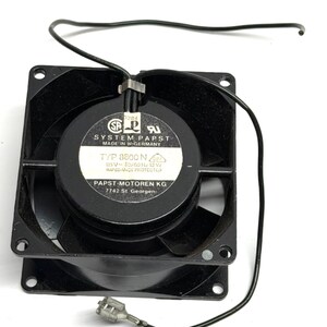 May include: A black square fan with a central circular component. The fan has a label with text including "SYSTEM PAPST" and "TYP 8800 N". Black wires extend from the fan, terminating in a connector. The fan is designed for 115V and 12W.