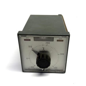 May include: An olive-green Weather Measure temperature controller with a black dial and a clear display. The dial shows temperatures in Fahrenheit, ranging from -100 to 400 degrees. The controller has "ON" and "OFF" indicators.