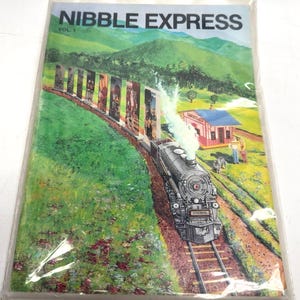 May include: A vintage book cover for "Nibble Express Vol. 1" featuring a steam train on tracks, passing by a train station. The cover art includes a green landscape with mountains and colorful panels along the train's path.