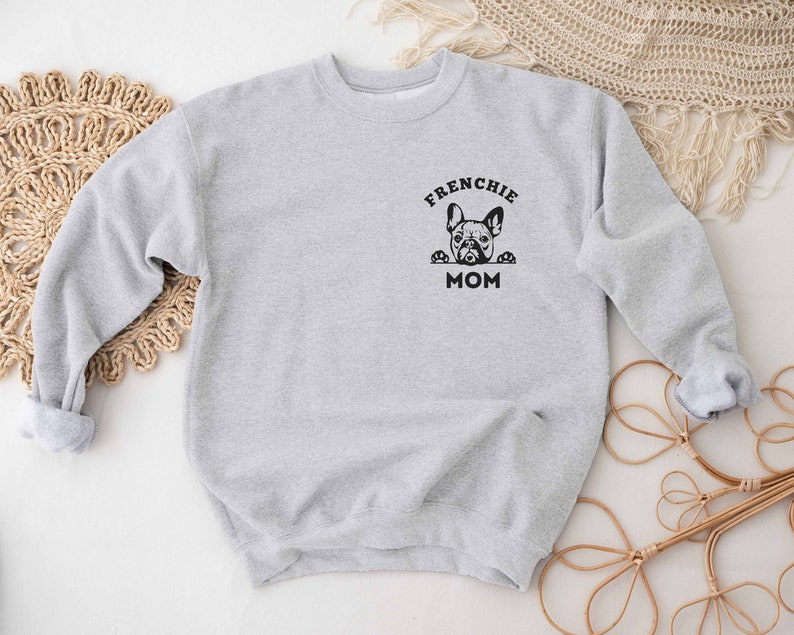 May include: Gray sweatshirt with a black graphic of a French bulldog peeking out of a box with the text "Frenchie Mom".