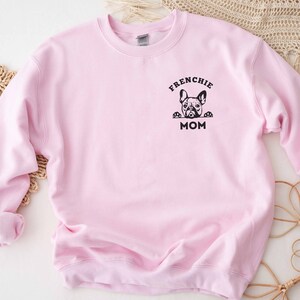 May include: Pink sweatshirt with a black graphic of a French bulldog peeking over the top and the text "Frenchie Mom".
