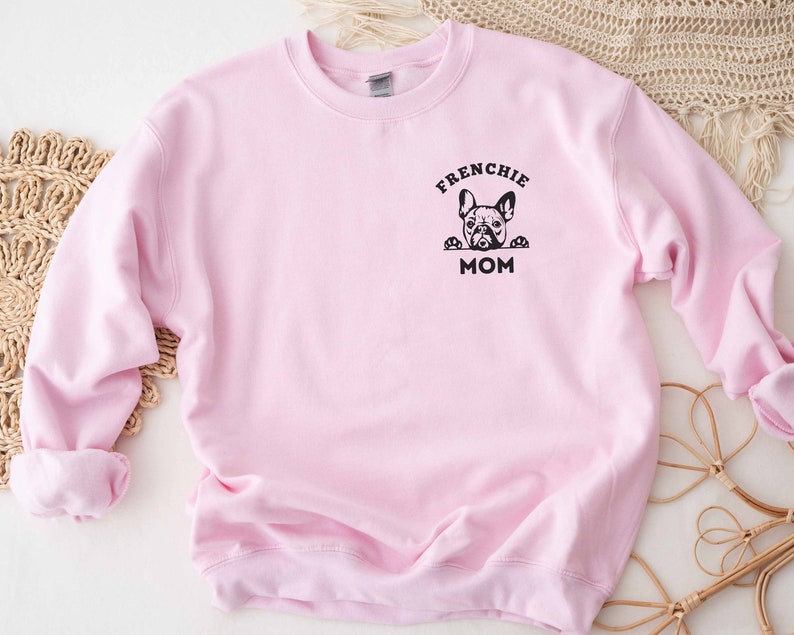 May include: Pink sweatshirt with a black graphic of a French bulldog peeking over the top and the text "Frenchie Mom".