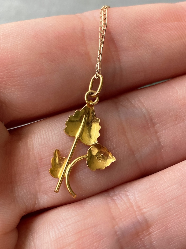 May include: A gold pendant necklace featuring a delicate design of three leaves. The pendant is marked "10K" on the reverse.