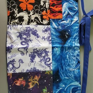 May include: A fabric roll-up organizer featuring a patchwork design of various dragon-themed patterns. The panels include black with orange flowers and white dragons, white with purple dragons, dark purple with small dragons, and blue space with large dragons.