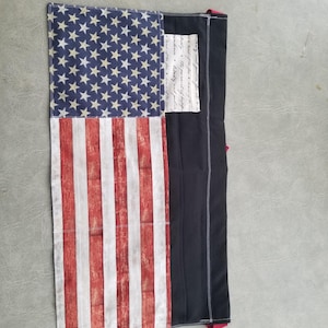 May include: A black and red apron with a distressed American flag design. The apron has a pocket with a handwritten quote that reads "We hold these truths to be self-evident, that all men are created equal, that they are endowed by their Creator with certain unalienable Rights, that among these are Life, Liberty and the pursuit of Happiness."
