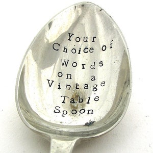 May include: A vintage silver table spoon with the text "Your Choice of Words on a Vintage Table Spoon" stamped into the bowl. The spoon has a classic design with a long handle and a rounded bowl, typical of a table spoon.