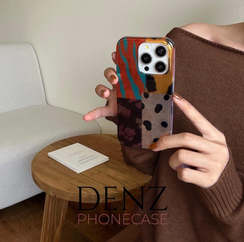 May include: A patterned phone case with a vibrant patchwork design. The case displays sections of red and teal stripes, yellow, brown, and black polka dots. The brand name "DENZ PHONECASE" is printed at the bottom.