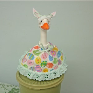 Desk goose dress for Easter in colorful eggs on white. White felt bunny ears.