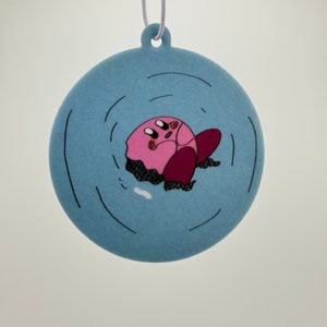 K&ouml;nnte beinhalten: Ein runder blauer und wei&szlig;er Anh&auml;nger mit einer rosa Comicfigur, Kirby, die im Wasser versinkt. Der Anh&auml;nger hat eine wei&szlig;e Schnur zum Aufh&auml;ngen.