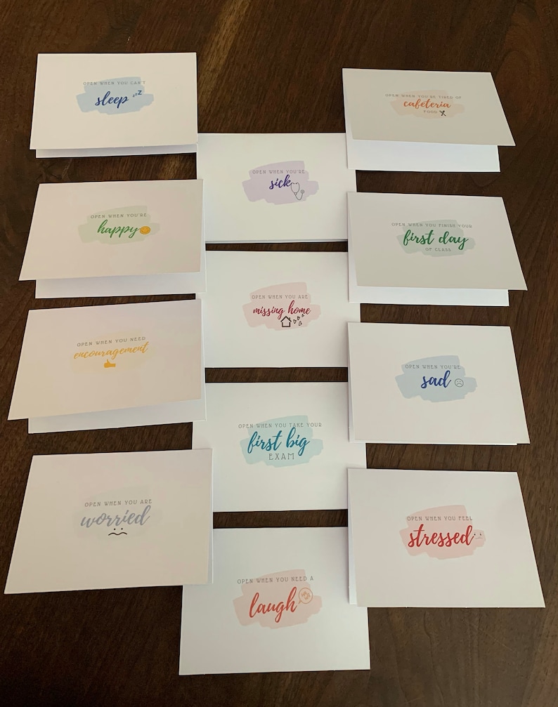 May include: A set of 10 cards with colorful watercolor backgrounds and encouraging messages. The messages include "Open when you can't sleep", "Open when you're happy", "Open when you need encouragement", "Open when you are worried", "Open when you need a laugh", "Open when you're sick", "Open when you are missing home", "Open when you take your first big exam", "Open when you finish your first day of class", and "Open when you feel stressed".