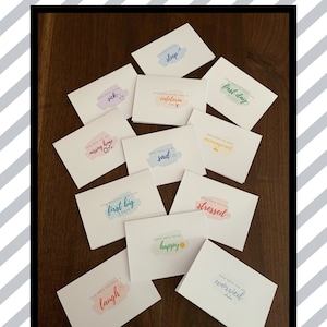 May include: A collection of colorful cards with watercolor-like designs and text that says "Open when you feel..." followed by a feeling, such as "sick", "sleep", "cafeteria", "first day", "missing home", "sad", "overwhelmed", "first big exam", "stressed", "happy", "laugh", and "worried".