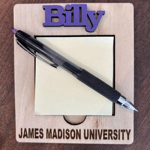 May include: A wooden notepad with a sticky note and a pen. The notepad has the name "Billy" and the text "JAMES MADISON UNIVERSITY" engraved on it.