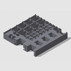 Può includere: Un vassoio di stoccaggio grigio con più scomparti, con aperture circolari e rettangolari. Ha una sezione superiore a griglia e fessure parallele sul lato. Il design suggerisce organizzazione e stoccaggio.