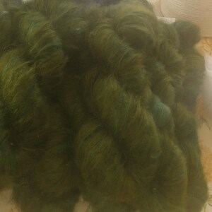 Pu&ograve; includere: Un mucchio di filato verde scuro con una texture leggermente screziata.