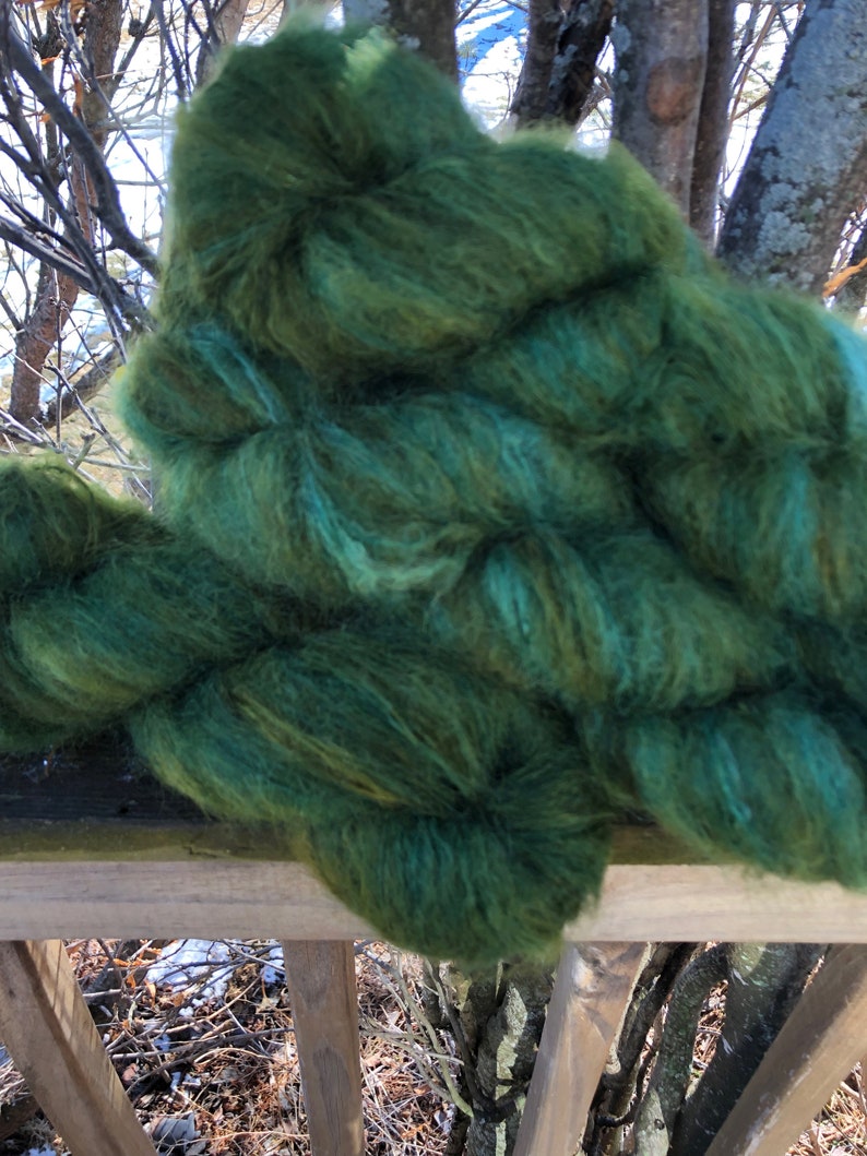 Pu&ograve; includere: Un gomitolo di filato verde e turchese con una consistenza soffice.