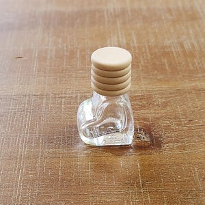 May include: A clear glass bottle with a cork stopper. The cork stopper is made of multiple layers of wood.