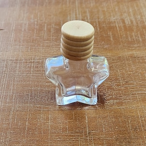 May include: A clear glass star-shaped bottle with a wooden lid. The lid is made of four stacked wooden circles.