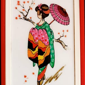 K&ouml;nnte beinhalten: Dekoratives Bild einer Geisha in einem farbenfrohen Kimono, die einen rosa Sonnenschirm h&auml;lt und in der N&auml;he eines Zweigs mit roten Bl&auml;ttern steht. Das Bild ist vor einem wei&szlig;en Hintergrund und rot-wei&szlig; gerahmt.