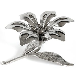 Peut inclure: Une sculpture de fleur argentée stylisée avec de grands pétales incurvés et des feuilles détaillées. La sculpture est en métal et a une surface réfléchissante. La fleur est montée sur une tige avec deux feuilles.