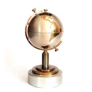 Pode incluir: Um globo decorativo com acabamento metálico, com base prateada e globo dourado. O globo é suportado por um suporte cor de latão e uma base prateada. A superfície do globo reflete a luz, destacando os continentes.