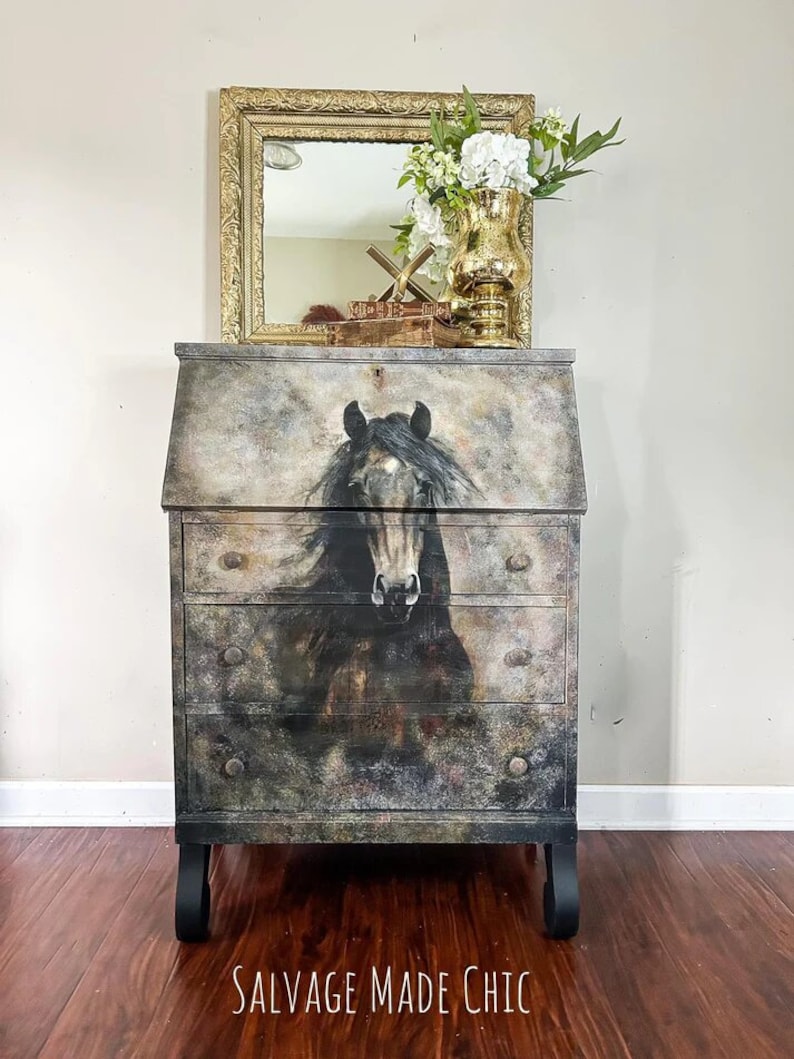 K&ouml;nnte beinhalten: Ein schwarzer Sekret&auml;r mit einem Pferdebild auf der Vorderseite. Der Schreibtisch hat drei Schubladen und eine herunterklappbare Front. Der Schreibtisch ist im Shabby-Chic-Stil mit einem dunklen Grau- und Braunton bemalt. Der Schreibtisch steht auf einem Holzboden. Der Text "SALVAGE MADE CHIC" befindet sich auf dem Boden vor dem Schreibtisch.