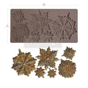 Può includere: Uno stampo in silicone marrone con disegni di fiocchi di neve, misura 25,4 cm per 12,7 cm. Sotto ci sono diversi fiocchi di neve fusi con una finitura dorata metallizzata. I fiocchi di neve variano per dimensioni e dettagli, adatti per progetti fai-da-te.