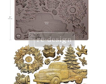 May include: A rectangular silicone mold measuring 8 inches by 5 inches, featuring embossed designs of a vintage pickup truck, Christmas tree, wreath, bells, bows, and gift boxes. Below, gold-colored cast versions of these same holiday shapes.