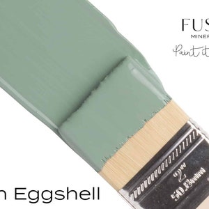 May include: A close-up of a paint brush with a light green paint sample. The paint is labelled "French Eggshell" and is part of the Fusion Mineral Paint line. The text "Paint it beautiful." is also visible.