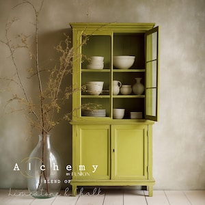 May include: A green painted cabinet with glass doors and shelves. The cabinet is filled with white bowls and plates. The cabinet is labelled "Alchemy by Fusion Blend of Limestone & Chalk".