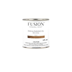 Może przedstawiać: Puszkę farby mineralnej Fusion Stain & Finishing Oil w kolorze orzechowym. Puszkę ma pojemność 8 uncji płynu i zawiera etykietę ostrzegawczą.