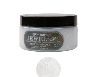 Puede incluir: Un tarro de "Jewel Effect Paste" con cristales triturados. El tarro es azul claro con una tapa negra y una etiqueta que dice "Crushed Crystals" y "100 ml". Se muestra una pequeña muestra de la pasta debajo.