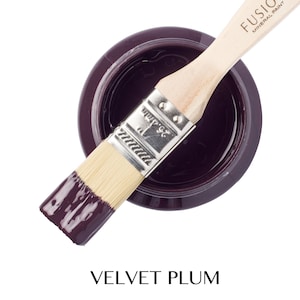 May include: A small jar of deep purple paint with a wooden paintbrush dipped in the paint. The jar is labelled "Fusion Mineral Paint" and the paint colour is "Velvet Plum".