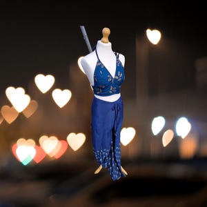 May include: A blue and gold floral print halter top and matching wrap skirt. The top has a sweetheart neckline and the skirt has a tie closure.