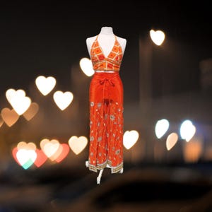 May include: Orange and white patterned crop top and matching wide-leg pants with embroidered details. The outfit is on a white mannequin against a blurry background of heart-shaped lights.
