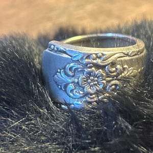 May include: A silver ring made from a repurposed spoon with a floral design.