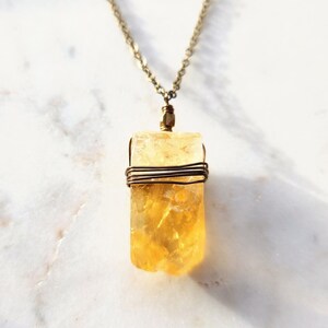 May include: A gold chain necklace with a wire-wrapped yellow citrine pendant.